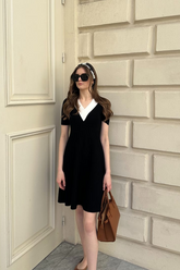 a lady in a black v-neck dress with white trim